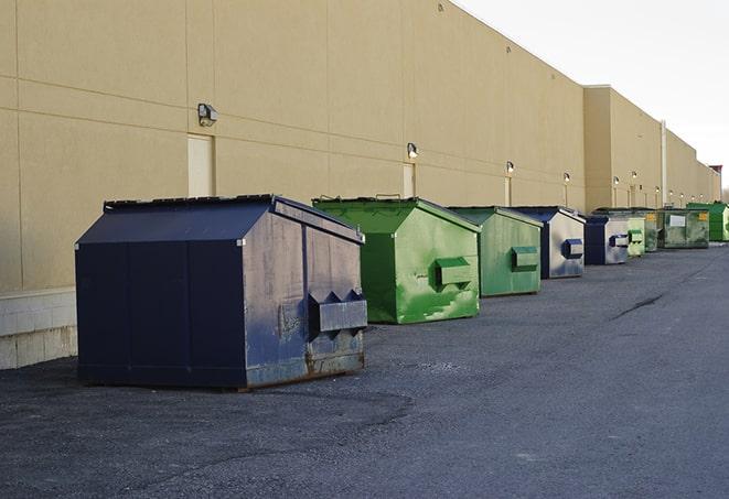 a waste management truck unloading into a construction dumpster in Carlsbad